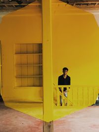 Full length of man standing by yellow door of building