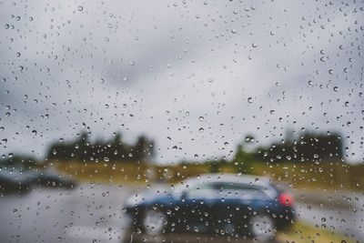 Close-up of waterdrops on glass against sky seen through wet window