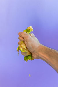Midsection of man holding fruit against blue sky