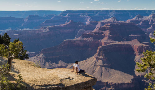 High angle view of man sitting on cliff against canyon