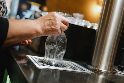 The hands of an elderly woman rinses a glass of beer.