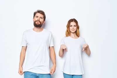 Portrait of young couple standing against white background