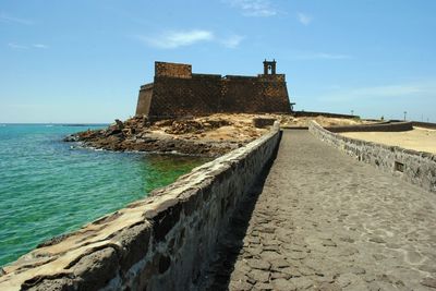 Scenic view of old building by sea against sky