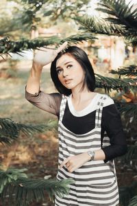 Portrait of young woman standing against plants