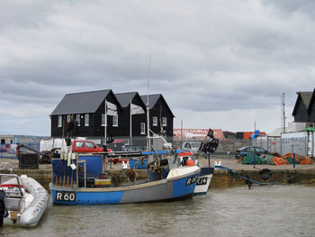 Boats in sea against cloudy sky