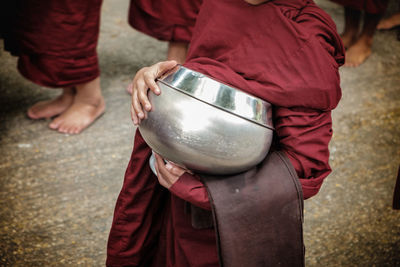 Midsection of man holding container while standing on street