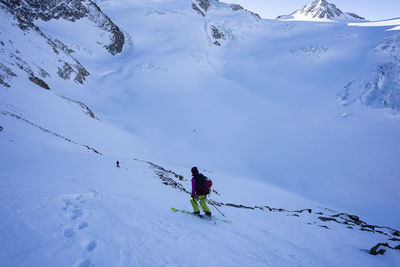 Rear view of woman skiing on snowcapped mountain