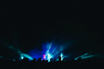 Silhouette people at music concert against sky at night