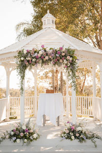 Beautiful white wedding gazebo with floral arrangements - pink roses and eucalyptus leaves