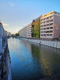 Canal amidst buildings in city against sky