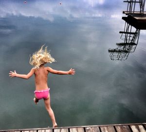 Full length of boy jumping in sea against sky