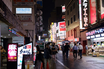 People walking on illuminated street at night