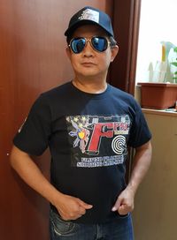 Portrait of man wearing sunglasses standing against wall