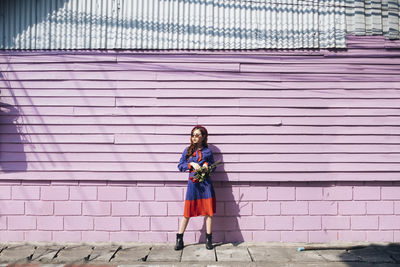 Portrait of woman standing against wall