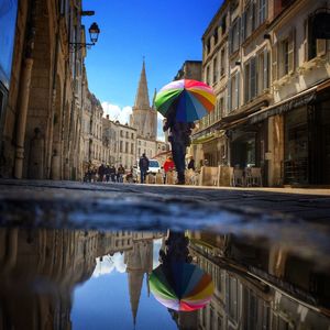 Low angle view of people walking on street amidst buildings in city