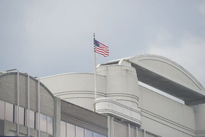 Low angle view of american flag waving on building against sky