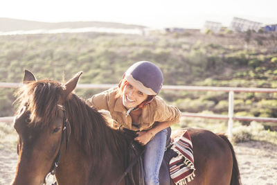 Portrait of smiling woman riding horse on landscape