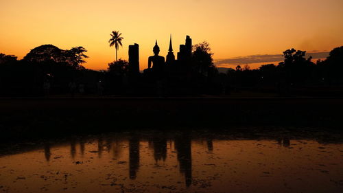 Silhouette trees by lake against sky during sunset