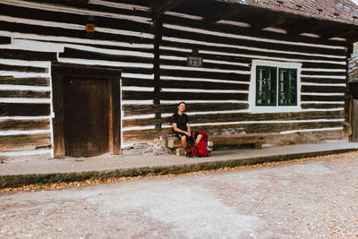 Side view of man sitting by house against building