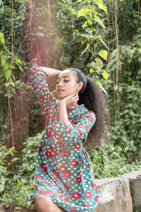 Portrait of young woman standing against trees