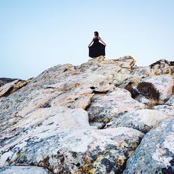 Rear view of woman standing on cliff against clear sky