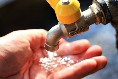 Water flowing from faucet on hand of person