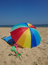 Multi colored umbrella on beach against clear blue sky