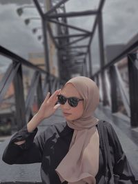 Woman wearing sunglasses on footbridge