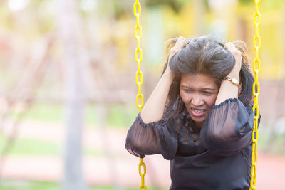 Tensed woman with head in hands sitting outdoors