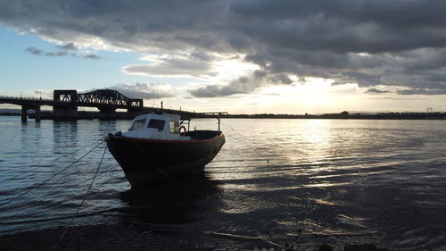 Boat moored on sea against sky during sunset