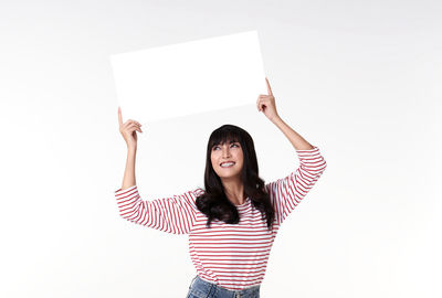 Portrait of smiling young woman standing against white background