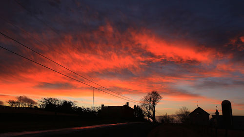 Silhouette trees and buildings against sky during sunset