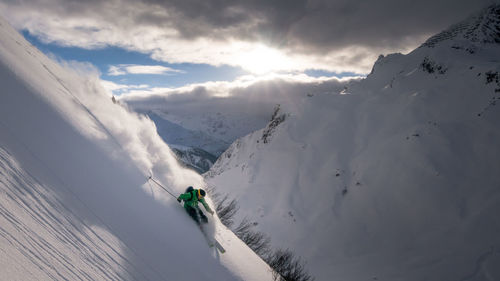 Man skiing on snowcapped mountain against sky