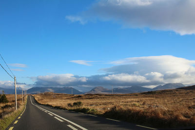 Empty road along landscape against sky