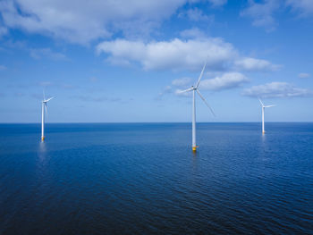 Wind turbines in sea against sky