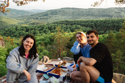 Portrait of smiling friends sitting on field