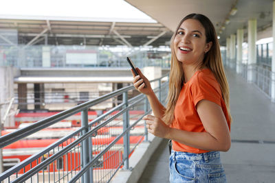 Brazilian woman using her mobile phone walking in train station of sao paulo metropolis, brazil