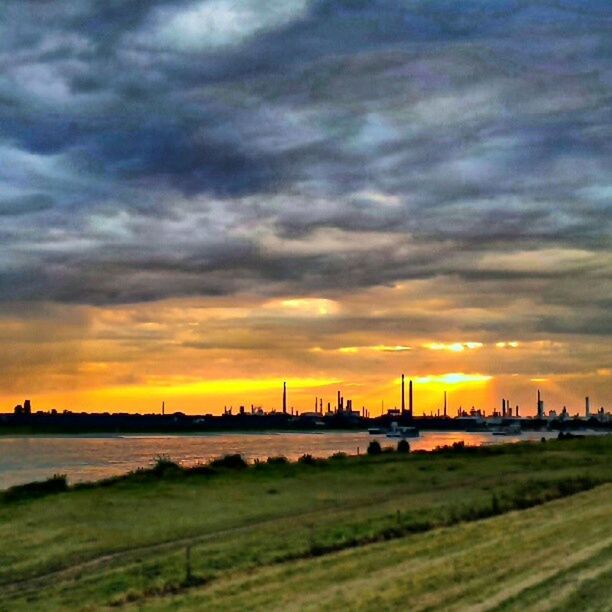 sunset, sky, water, cloud - sky, orange color, scenics, sea, beauty in nature, cloudy, tranquil scene, tranquility, dramatic sky, nature, idyllic, built structure, cloud, river, architecture, silhouette, beach