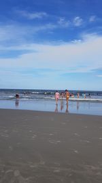 Men standing on beach against sky