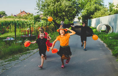 Happy boys and girls wearing halloween costume running on road