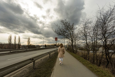 Rear view of woman walking on road against sky