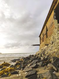 Rocks on beach by sea against sky