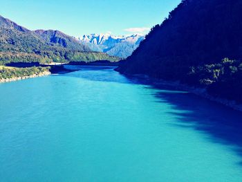 Scenic view of river amidst mountains against clear blue sky