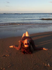 Woman on beach by sea against sky during sunset