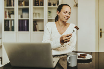 Young woman using laptop in coffee cup