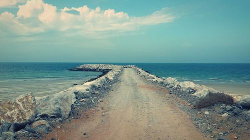 Walkway at beach against sky