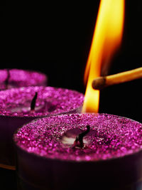 Close-up of matchstick and lit tea light candle