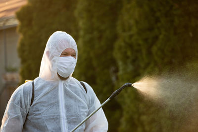 Close-up of man in protective suit spraying chemicals