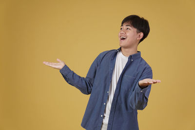 Young man looking away against yellow background