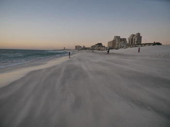 Scenic view of beach against clear sky during sunset